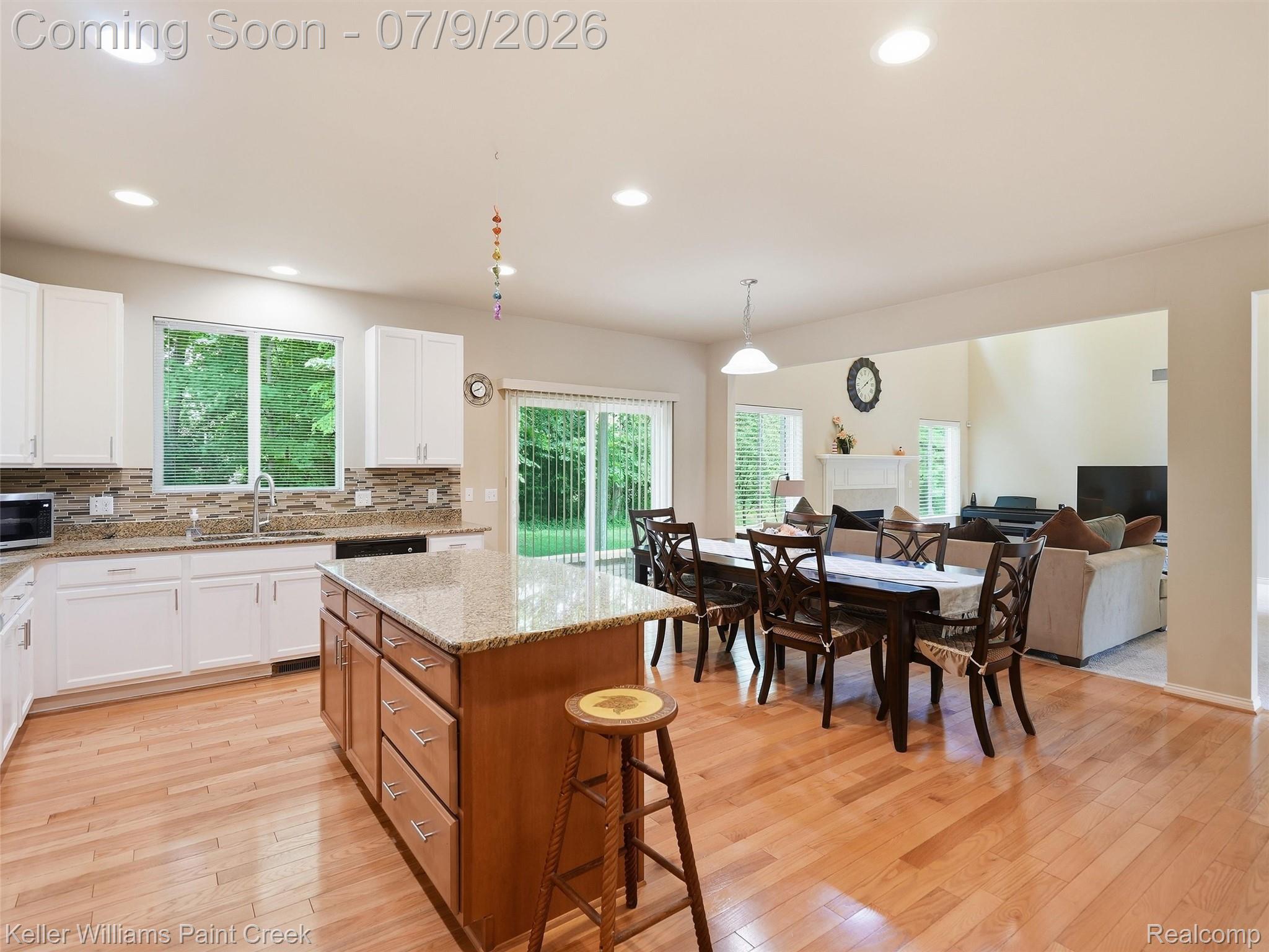 846 Monterey Ln. Rochester, MI 48307 - Photo 18 of 52 Open-concept kitchen featuring wood-finish flooring, white cabinetry, a stone-finish backsplash, and a large central island with a stone-finish countertop
