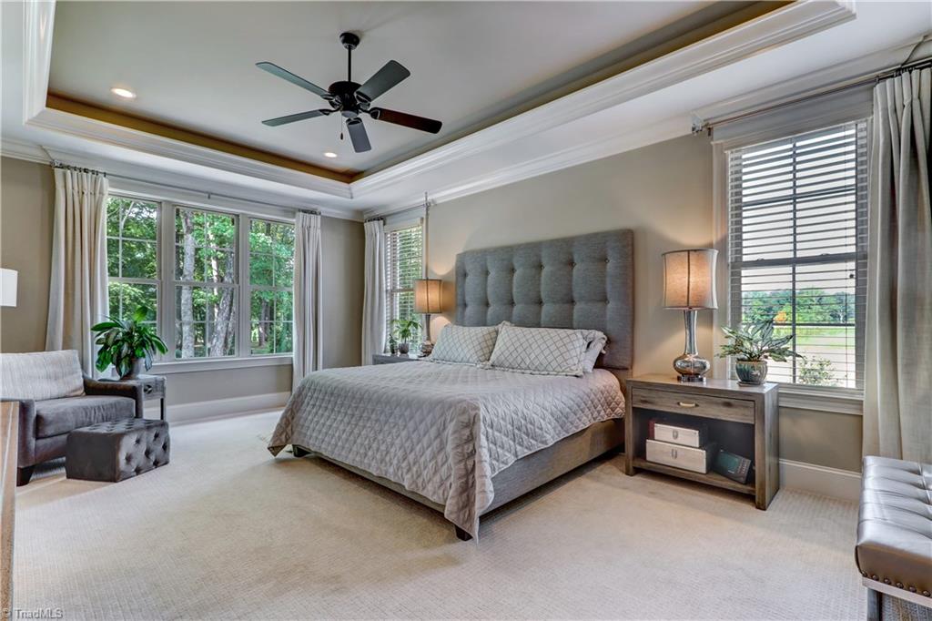 6865 Matzinger Court Oak Ridge, NC 27310 - Photo 11 of 28 The Master Bedroom is a place you can lose yourself every night! Linger over the outdoor views by day, but enjoy the tray ceiling with LED lighting, recessed accent lighting, ceiling fan, and luxurious carpeting all the time.