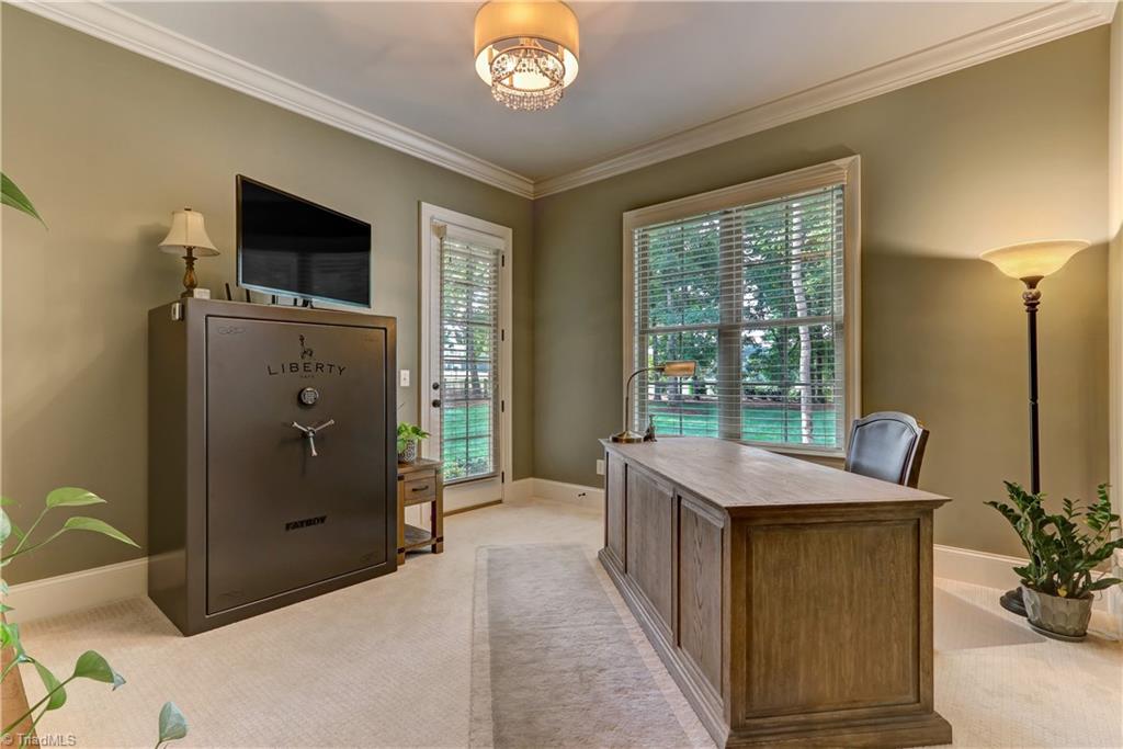 6865 Matzinger Court Oak Ridge, NC 27310 - Photo 15 of 28 This room is used as an office, but could also be another bedroom on the main floor. Door leads to outdoor patio. Wall to wall carpeting, base and crown molding, and ceiling chandelier.