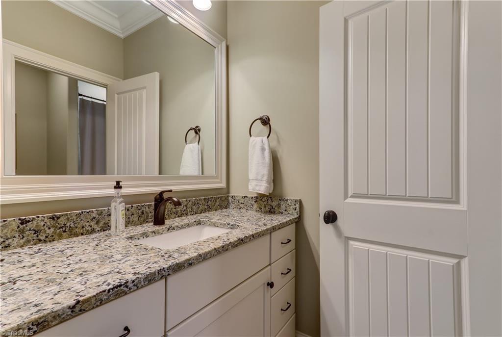 6865 Matzinger Court Oak Ridge, NC 27310 - Photo 19 of 28 All bathrooms feature granite countertops and, under mount sinks, framed mirrors, and sconce lighting.
