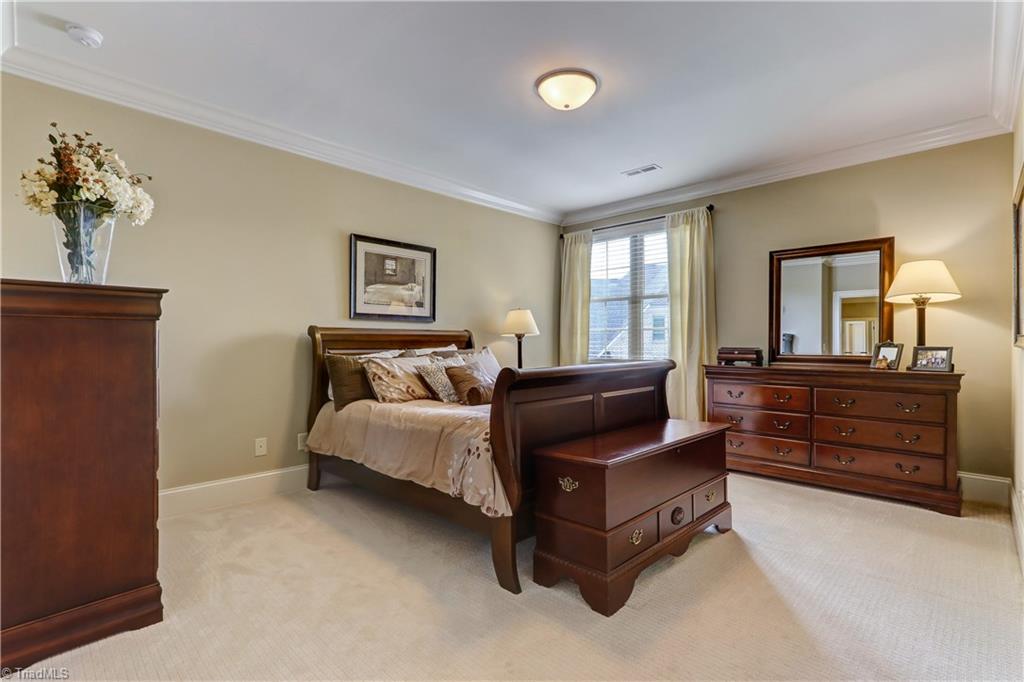 6865 Matzinger Court Oak Ridge, NC 27310 - Photo 21 of 28 Bedroom 4 has a large walk in closet, wall to wall carpeting, base and crown molding, ceiling light, and wood blinds. Attached bath.