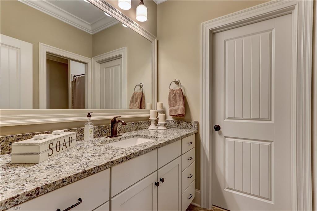 6865 Matzinger Court Oak Ridge, NC 27310 - Photo 22 of 28 The bath for Bedroom 4. Granite counter top, under mount sink, designer faucet, over head ceiling and sconce lighting.
