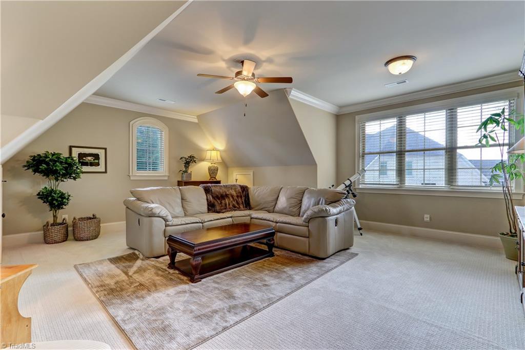 6865 Matzinger Court Oak Ridge, NC 27310 - Photo 24 of 28 Bonus Room, wall to wall carpeting, base and crown molding, ceiling fan with light and additional ceiling light in window alcove. Arched window has plantation shutter.