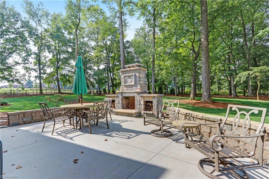 6865 Matzinger Court Oak Ridge, NC 27310 - Photo 25 of 28 The backyard patio has plenty of room for multiple seating groups and is surrounded by a seating wall. Wood burning fireplace with covered storage for wood.