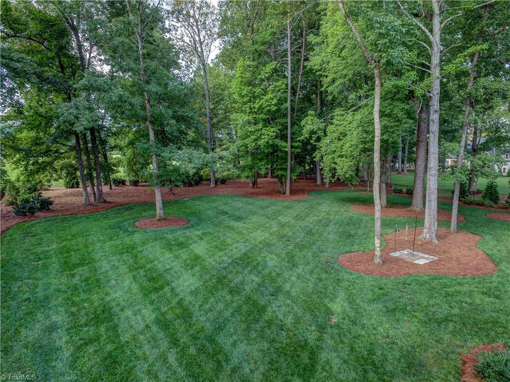 6865 Matzinger Court Oak Ridge, NC 27310 - Photo 26 of 28 Professionally landscaped by New Garden Landscaping, this back yard feels like a park. The perfect blend of trees and open space, grass, mulch and planting beds.