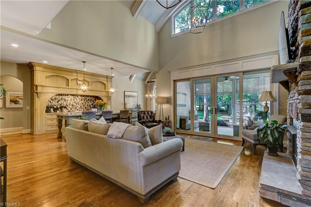6865 Matzinger Court Oak Ridge, NC 27310 - Photo 3 of 28 Hardwood flooring continues into the large two-story Great Room. Two chandeliers lend architectural significance to the barrel vaulted ceiling. Extensive use of wood moldings around the double sliding door to the Screened Porch.