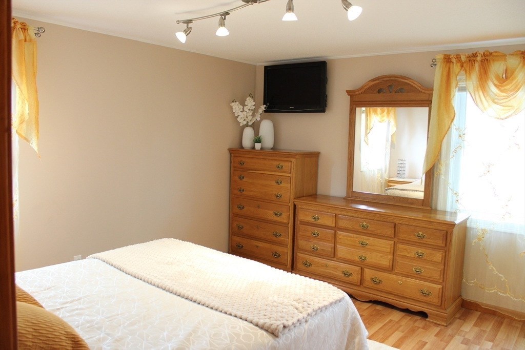 28 State Street Chicopee, MA 01013 - Photo 13 of 25 a bedroom with a bed and a flat tv screen on dresser