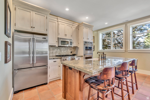 2579 Splendor Valley Road Kamas, UT 84036 - Photo 55 of 87 Two tone kitchen with stainless steel appliances, tasteful backsplash, a center island with sink, a kitchen bar, and recessed lighting