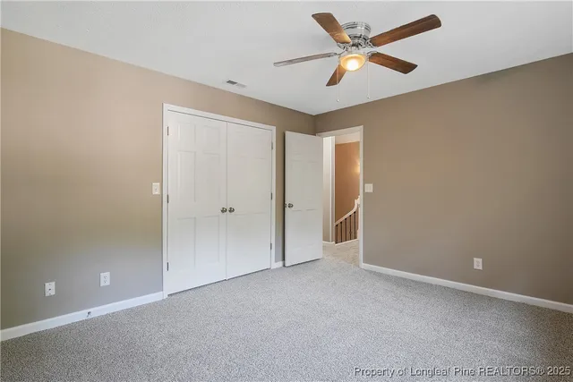 an empty room with closet and a ceiling fan