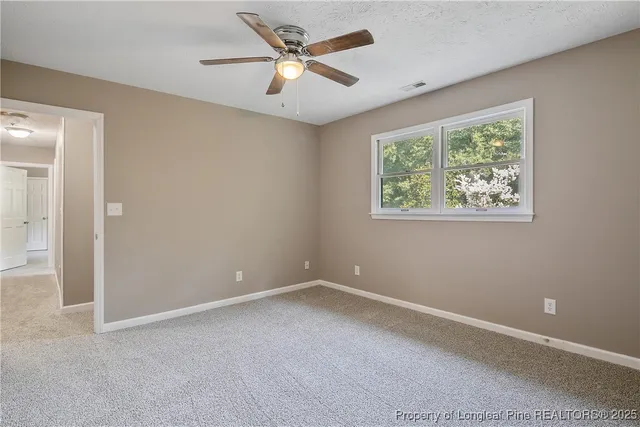 an empty room with a window and a fan