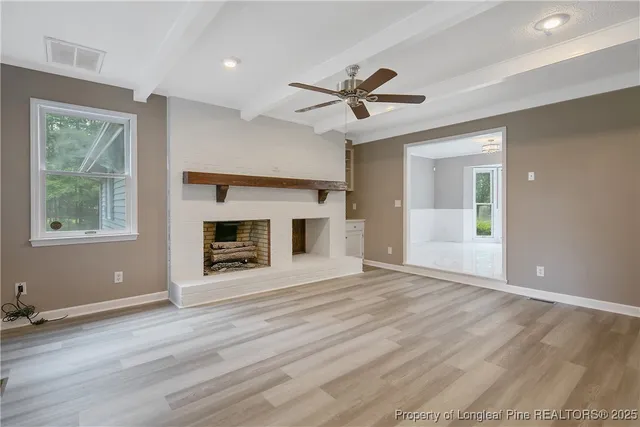 a view of an empty room with window and wooden floor