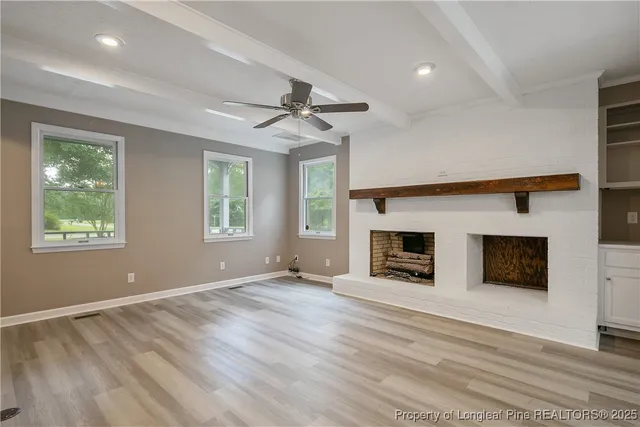 an empty room with windows and fireplace