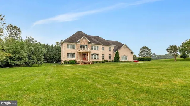 a view of a big house with a big yard and large trees