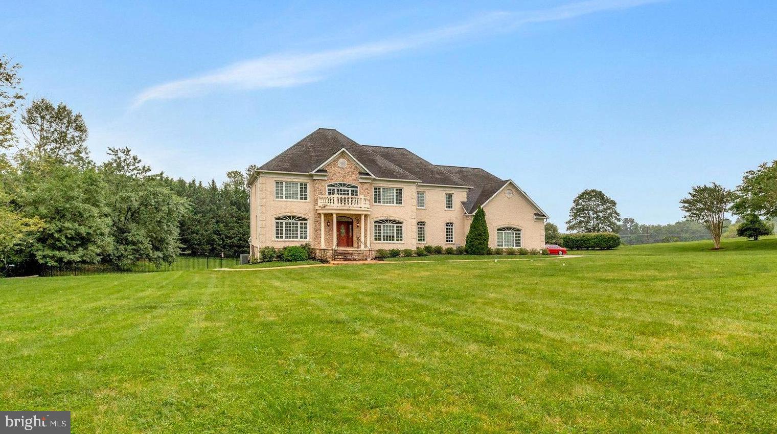 a view of a big house with a big yard and large trees