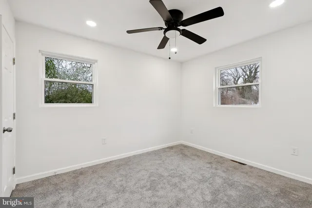 an empty room with a window and a ceiling fan