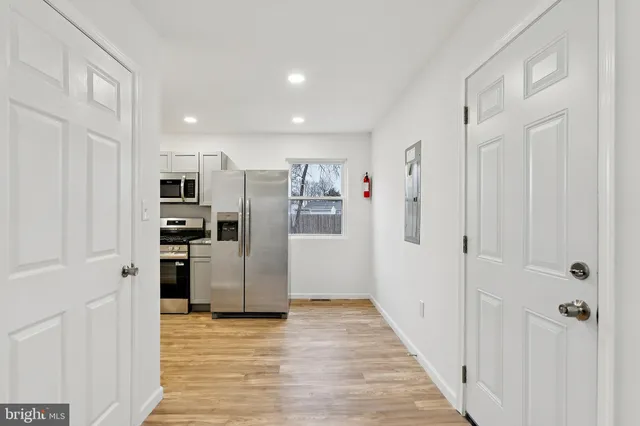 a view of a kitchen with refrigerator and a wooden floor