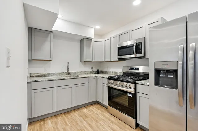 a kitchen with stainless steel appliances granite countertop a stove top oven a sink and a refrigerator