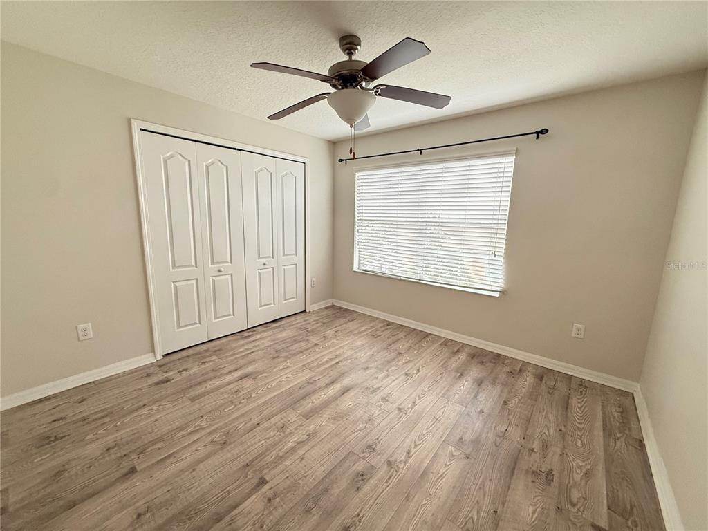 9854 Trumpet Vine Loop, Unit 9854 Trinity, FL 34655 - Photo 12 of 19 an empty room with wooden floor ceiling fan and windows