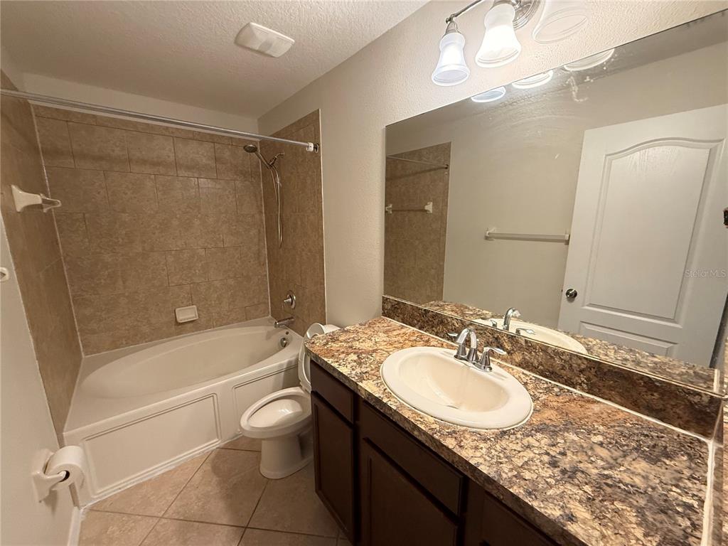 9854 Trumpet Vine Loop, Unit 9854 Trinity, FL 34655 - Photo 17 of 19 a bathroom with a granite countertop sink a mirror and a bathtub