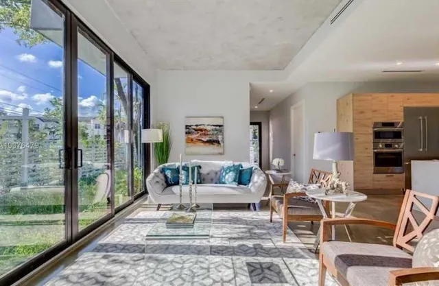 a living room with furniture large windows and wooden floor