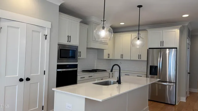 a kitchen with stainless steel appliances granite countertop a refrigerator a sink a stove and a refrigerator with wooden floor