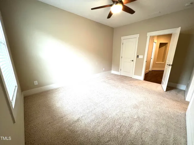 an empty room with chandelier fan and windows