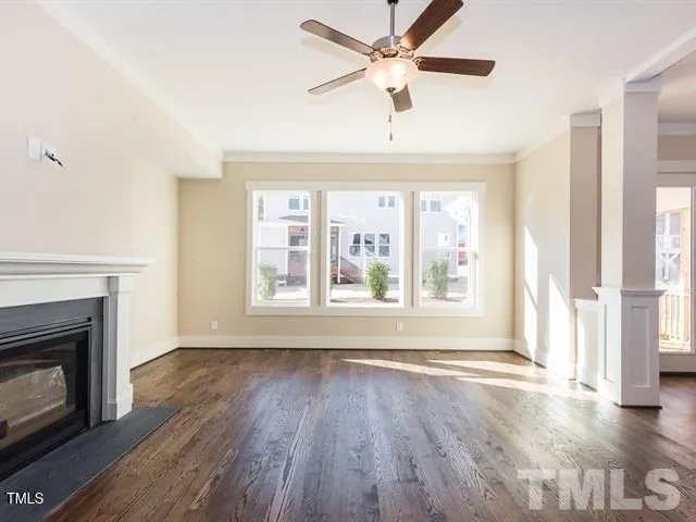 a view of an empty room with wooden floor fireplace and a window