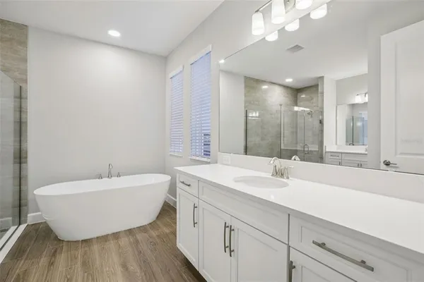 a spacious bathroom with a double vanity sink mirror and bathtub