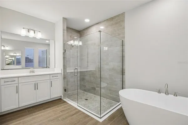 a bathroom with a bathtub shower sink mirror and toilet