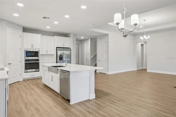 a kitchen with stainless steel appliances a chandelier and wooden floor