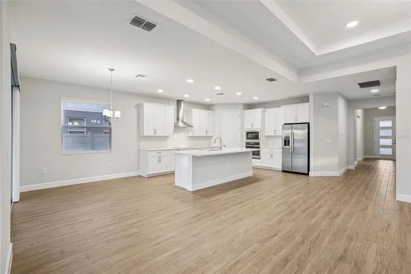 an open kitchen with white cabinets wooden floor and stainless steel appliances
