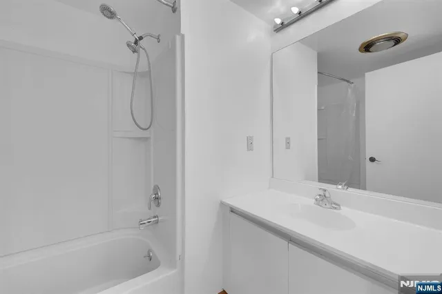 a bathroom with a tub a sink and mirror
