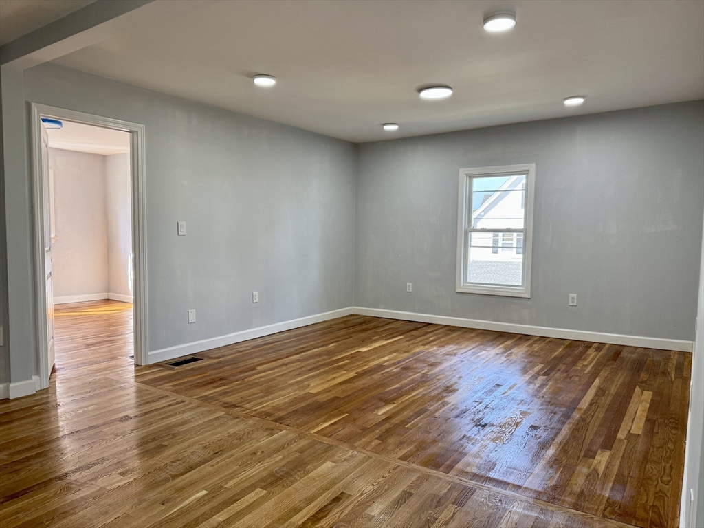 201 Belmont Street, Unit 2 Everett, MA 02149 - Photo 8 of 19 an empty room with wooden floor and windows