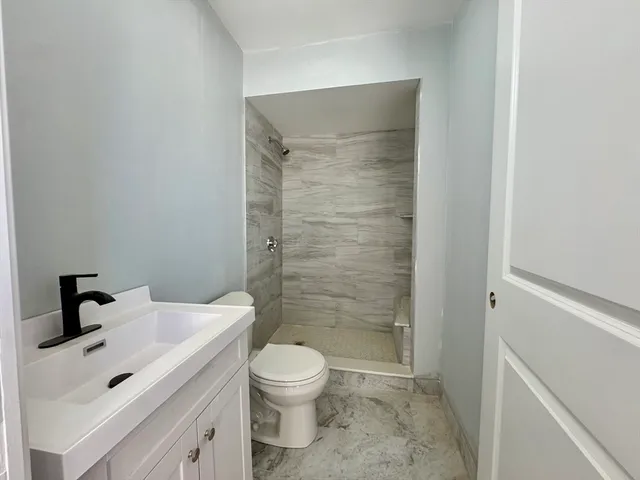 a bathroom with a sink a toilet and shower