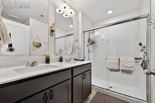 a bathroom with a double vanity sink mirror and shower