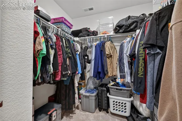 a view of walk in closet with clothes and shoes