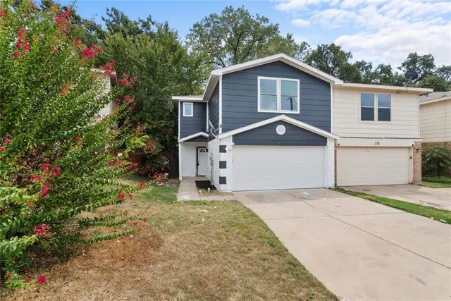 a view of a house with a yard and large tree