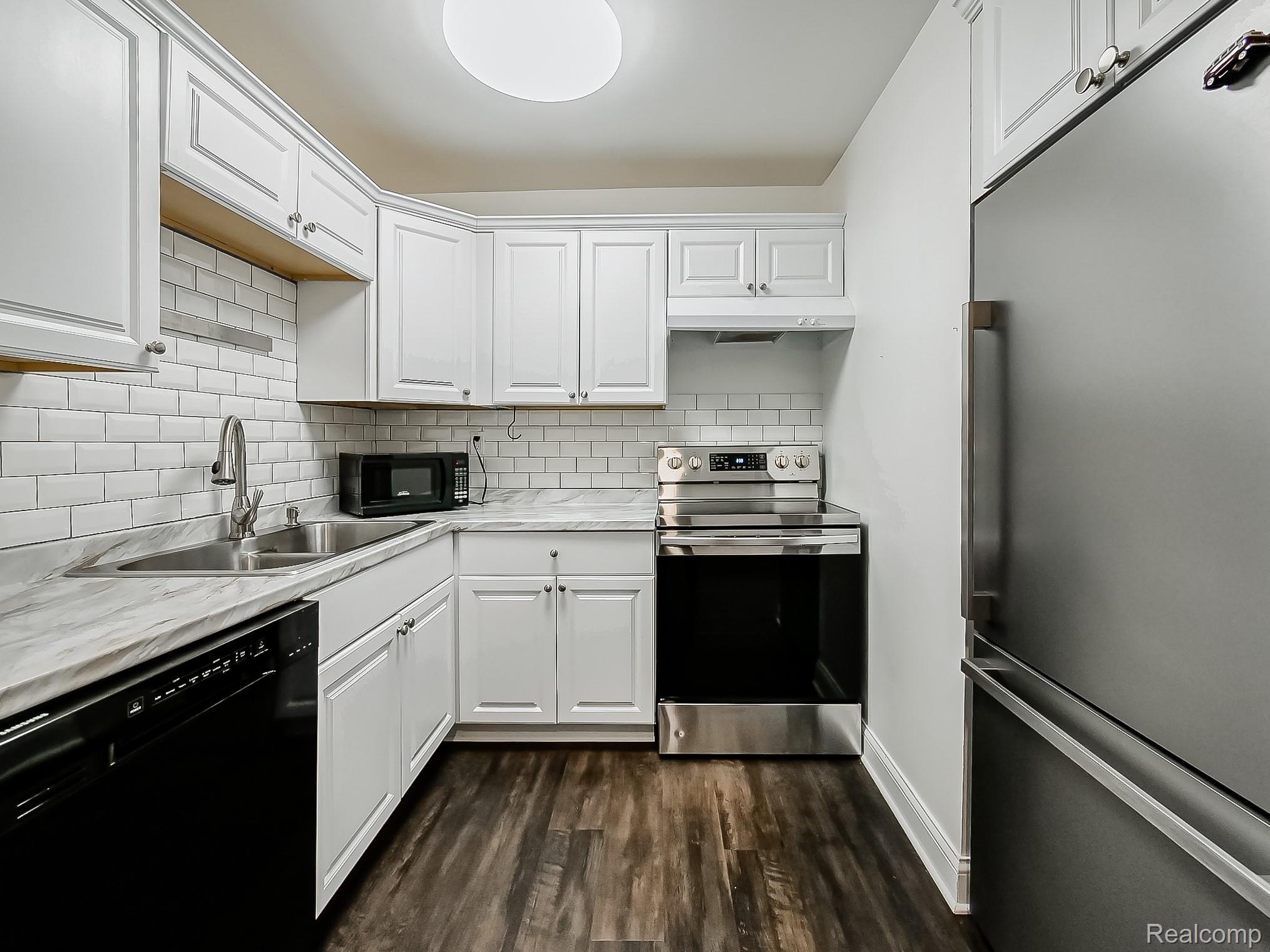 4905 South Crooks Road Royal Oak, MI 48073 - Photo 7 of 28 Kitchen featuring black appliances, light countertops, white cabinetry, dark wood-type flooring, and decorative backsplash