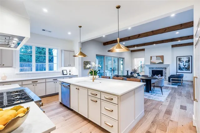 a large kitchen with stainless steel appliances granite countertop a stove oven a sink dishwasher and a fireplace with wooden floor