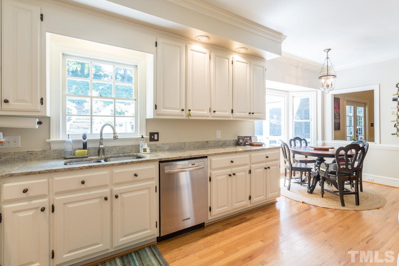 2206 Oxford Road Raleigh, NC 27608 - Photo 9 of 25 a kitchen with granite countertop white cabinets white appliances with a dining table and chairs
