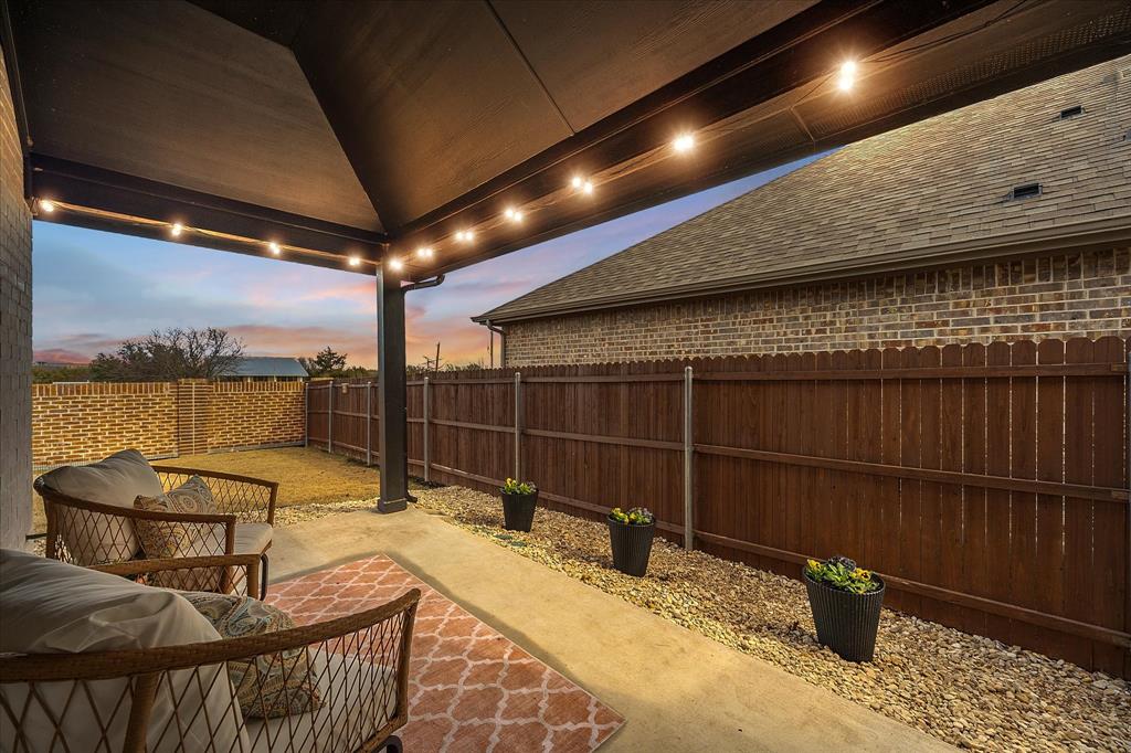 809 Mildren Lane Fate, TX 75087 - Photo 24 of 32 Another view of the patio and the backyard area. Wooden fence on the sides and brick wall in the back.