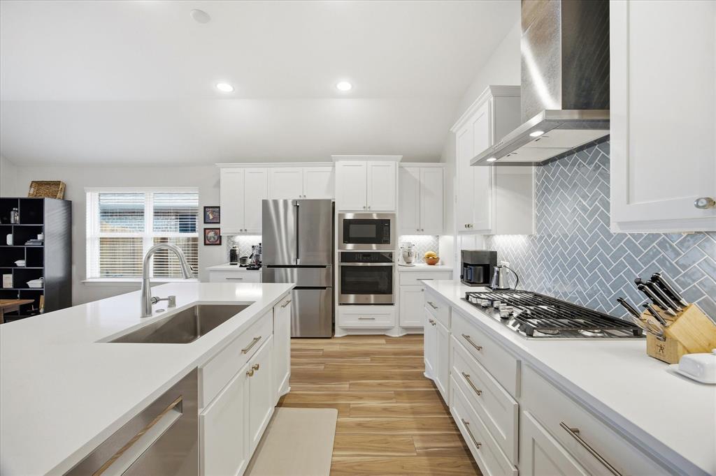 809 Mildren Lane Fate, TX 75087 - Photo 5 of 32 Notice the herringbone tile design above the stove top. Stainless appliances with a modern vented hood over the gas stove. Spacious cabinet and counter space in this kitchen.