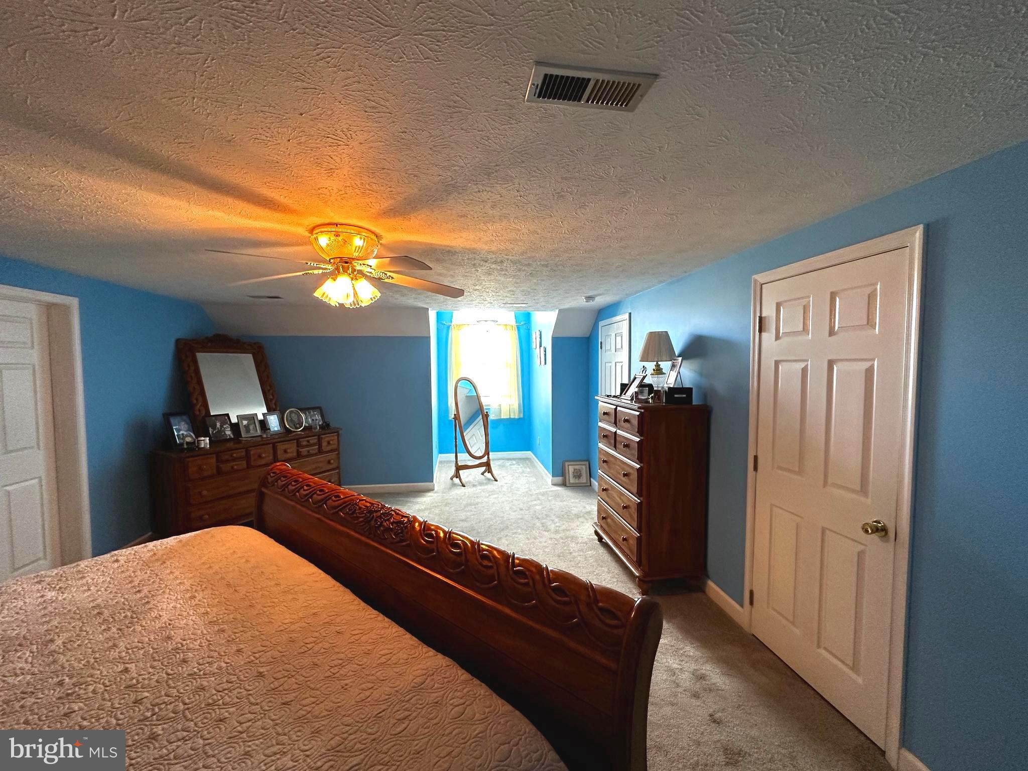 25 Mish Road Bunker Hill, WV 25413 - Photo 59 of 87 a bedroom with a bed a mirror on dresser and a chandelier