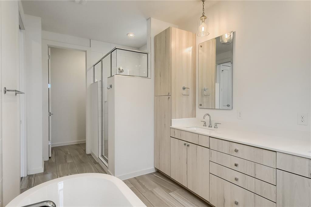2624 Metcalfe Road, Unit 7 Austin, TX 78741 - Photo 16 of 31 Contemporary bathroom featuring a freestanding tub, glass-enclosed shower, light wood-finish cabinetry, white countertop, and wood-finish flooring