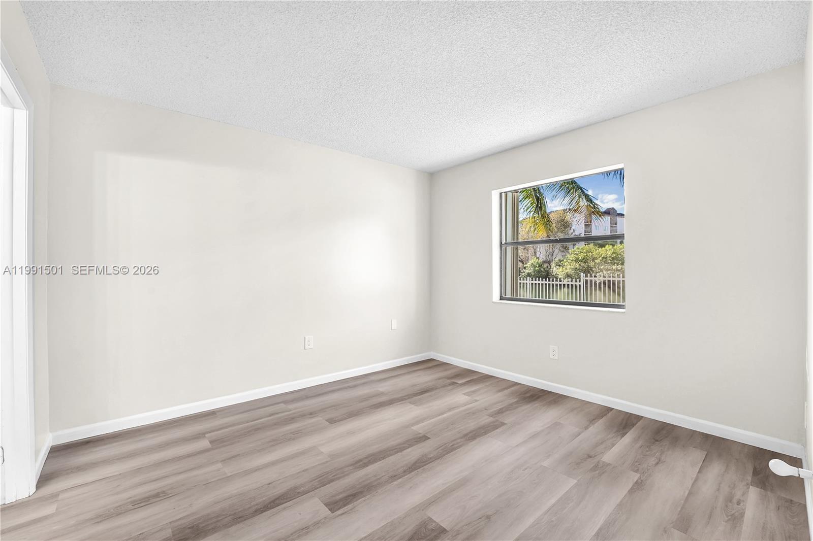 7668 Southwest 152nd Avenue, Unit 2107 Miami, FL 33193 - Photo 15 of 17 an empty room with wooden floor and window