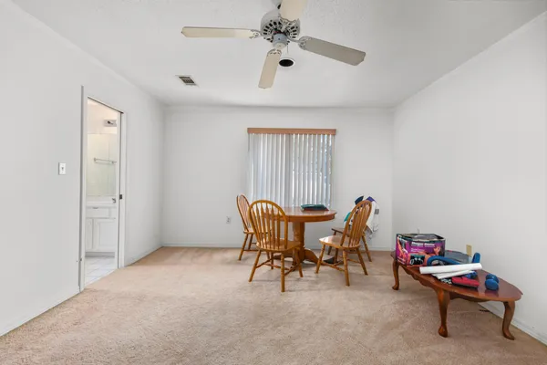 a work room with furniture a rug and a ceiling fan