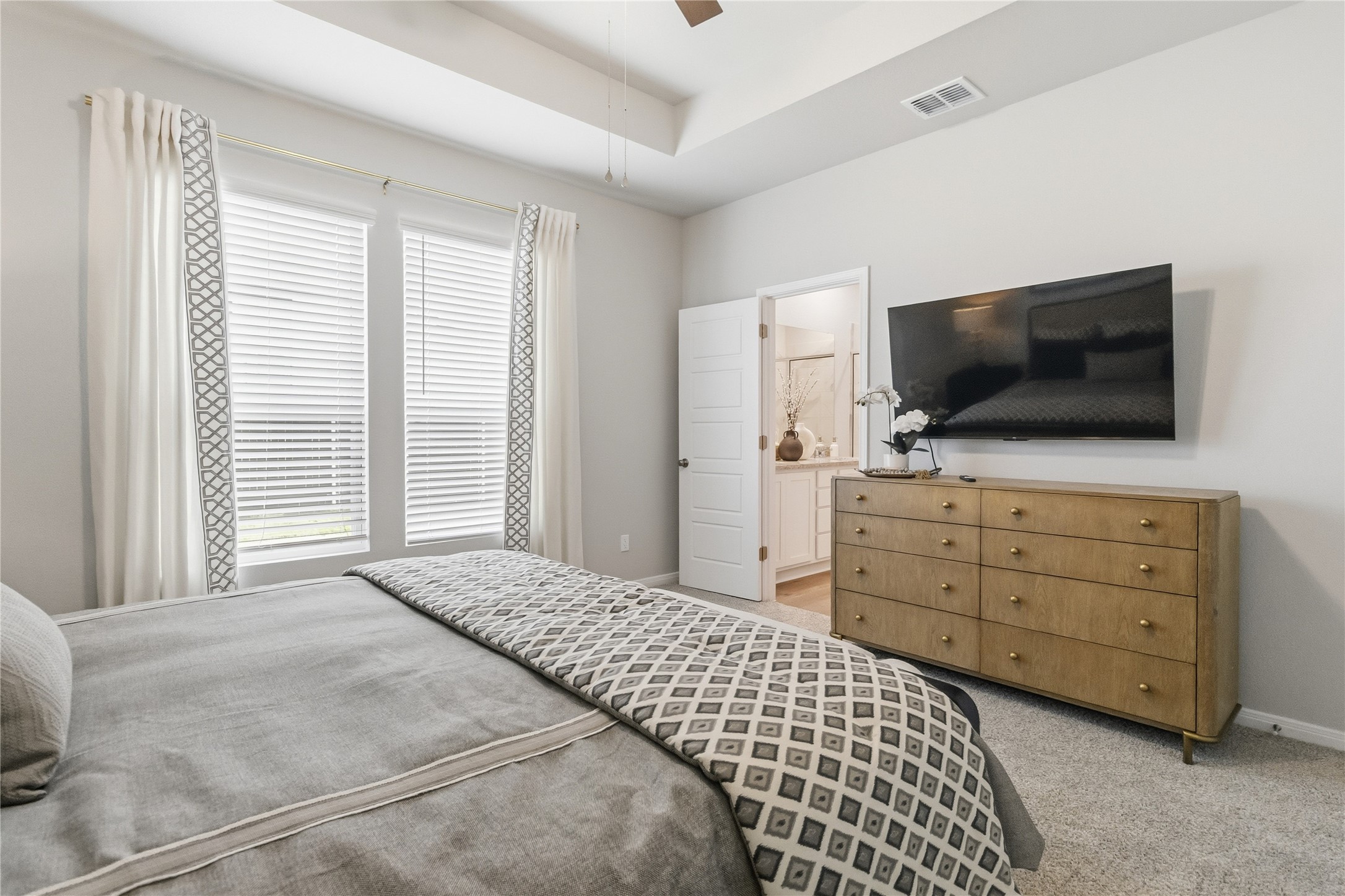 A tray ceiling and plush carpeting define this serene private bedroom retreat.