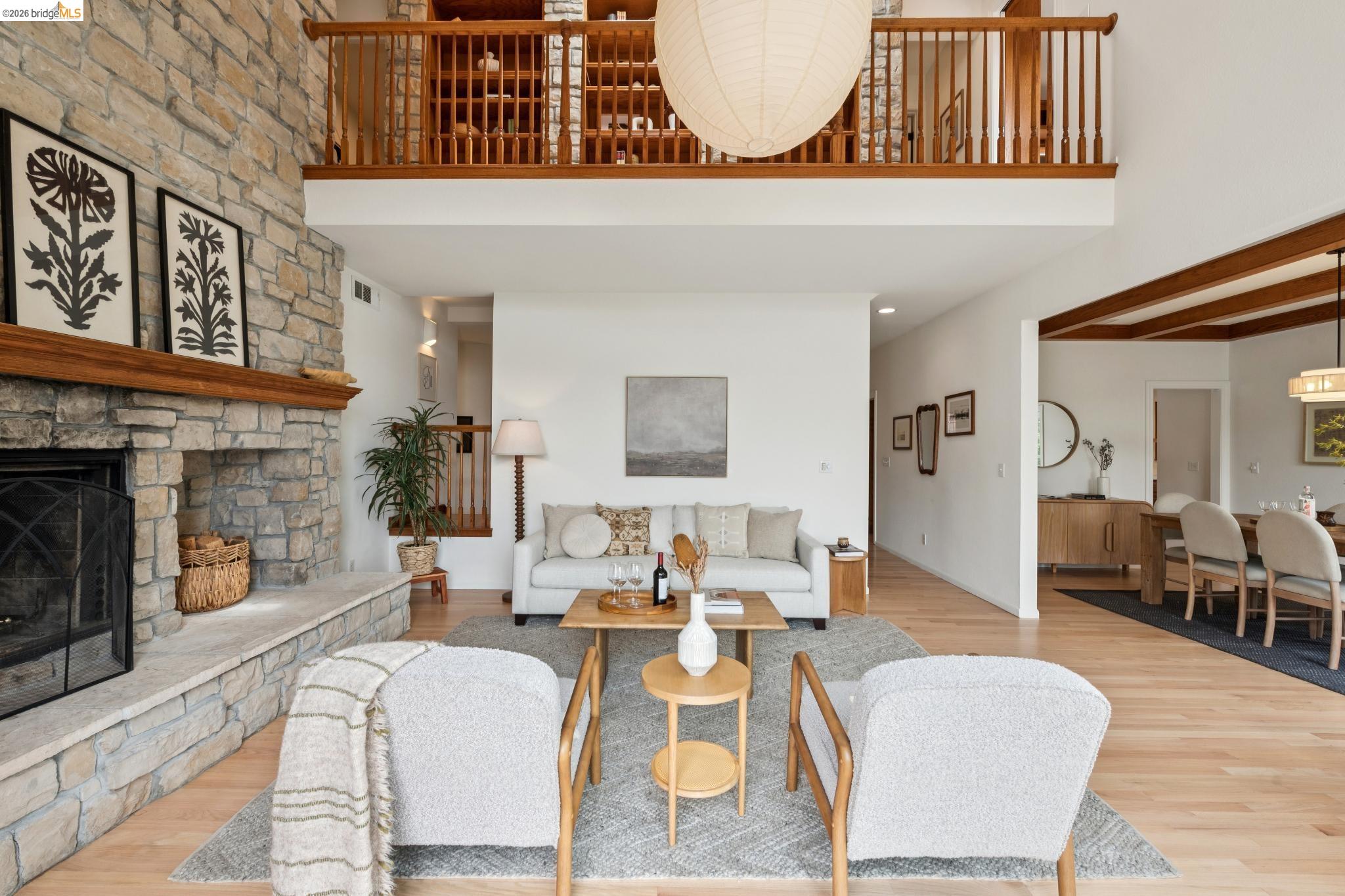 1325 Drury Road Berkeley, CA 94705 - Photo 17 of 71 Spacious living area featuring a stone fireplace with a wood mantle, hardwood flooring, and a second-story balcony overlooking the space