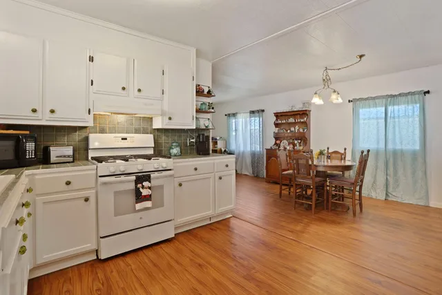a kitchen with stainless steel appliances white cabinets and wooden floor
