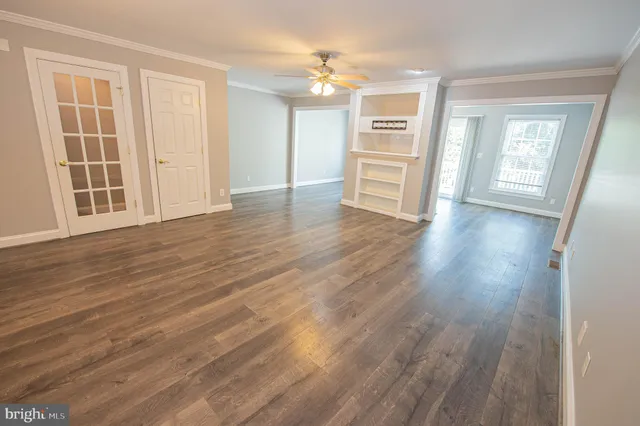 an empty room with wooden floor cabinet and windows